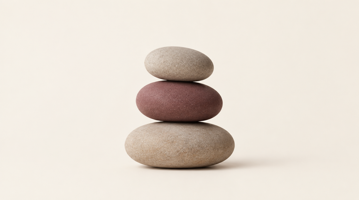 Tres piedras lisas en equilibrio sobre fondo crema